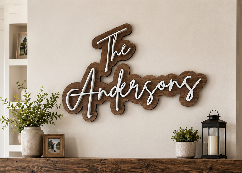 A rustic wooden wall sign reading 'The Andersons' in white script is mounted above a stone fireplace mantel in a cozy living room setting with plants, a lantern, and a visible fire.